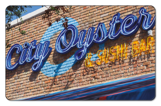 City Oyster neon sign attached to a brick wall.